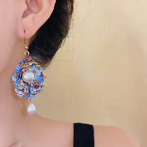 Detail view of ethnic style enamel flower earring with white pearls worn by a model