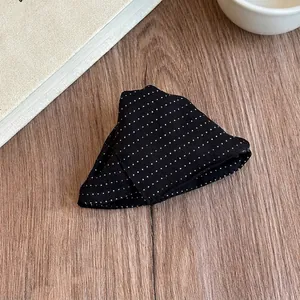 Detailed close-up of a stylish black hair claw clip with white polka dot bow design