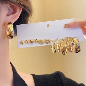 Elegant golden earring set featuring heart studs and twisted hoops on display card