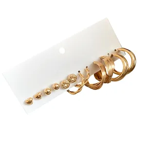 Elegant golden earring set featuring heart studs and twisted hoops on white card