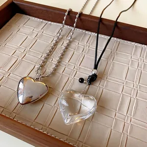 Minimalist silver and transparent heart pendant necklaces on a textured display tray