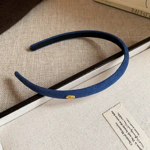 Detailed view of a navy blue slim flocked headband with a gold Love engraved metal tag