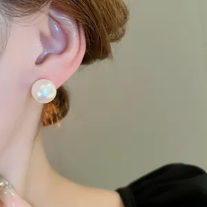 Primo piano di un elegante orecchino a bottone con perla bianca indossato, lucentezza morbida.