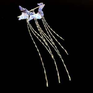 Detailed view of an elegant purple butterfly ear clip with long golden tassel chains
