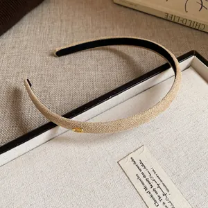 Detailed macro view of a beige flocked fabric thin headband featuring a golden 'Love' metal tag.