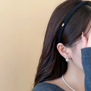Detailed view of a minimalist black flocked fabric headband worn on a model's hair.