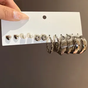 Detail view of silver earring set with heart studs, pearls, and textured hoop designs