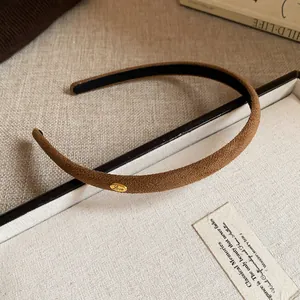 Macro view of brown flocked fabric headband with gold Love charm detail