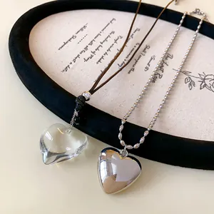 Close-up of minimalist clear and silver heart pendant necklaces on decorative tray