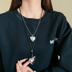 Detailed view of layered heart pendants on silver bead chain and black cord