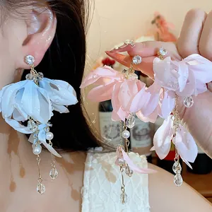 Dettaglio di eleganti orecchini a fiore in tessuto con perle e pendenti