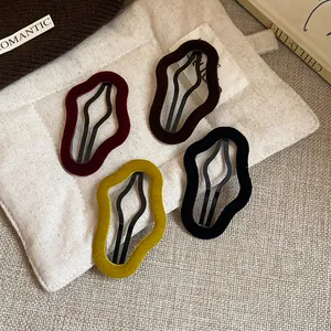 Detail showing four irregular flocked hair clips in burgundy, brown, yellow and black