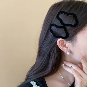 Detailed close-up view of elegant black flocked irregular geometric hair clips on model