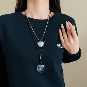Elegant layered long heart pendant necklace shown on a model wearing a black sweatshirt