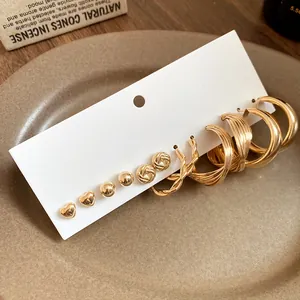Detail view of 6-pair golden earring set with heart, stud, and twisted hoop designs.