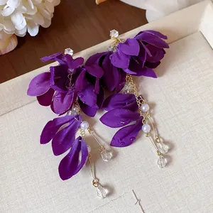Dettaglio di orecchini a fiore in tessuto viola con perle e cristalli su un vassoio.