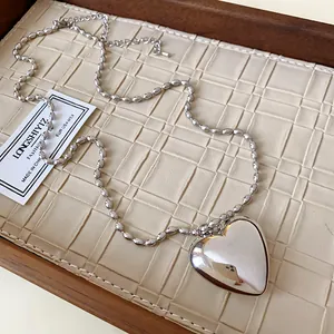 Close-up of a stylish silver rice bead necklace featuring a large polished heart pendant