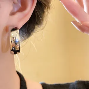 Close-up detail showing the sleek mirror-finish of a thick silver hoop earring worn on ear
