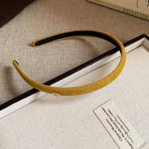 Close-up of a mustard yellow fabric headband with a gold 'Love' tag on a white box