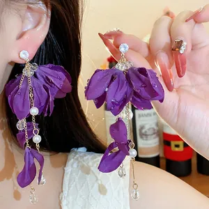 Dettaglio di eleganti orecchini a fiore in tessuto viola con perle e cristalli.