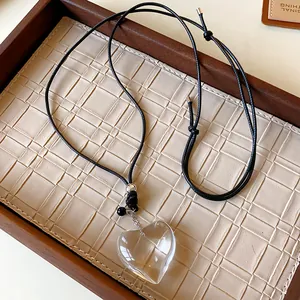 Macro detail of a transparent heart pendant necklace displayed in a luxury tray