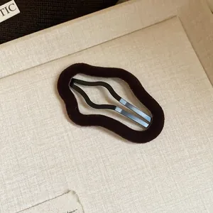 Close-up of irregular geometric flocked hair clip with dark brown velvet texture