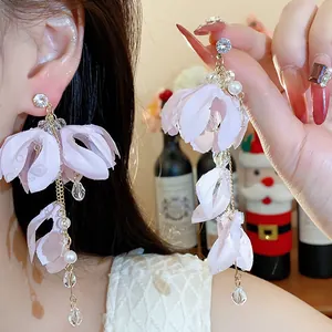 Primo piano di eleganti orecchini a fiore in tessuto rosa con perle e cristalli