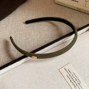 Close-up of thin olive green flocked headband with gold Love tag detail