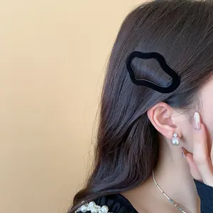 Detailed close-up view of a black flocked irregular geometric hair clip worn on long dark hair