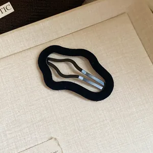 Macro detail of a minimalist black flocked wavy BB hair clip with soft velvet texture