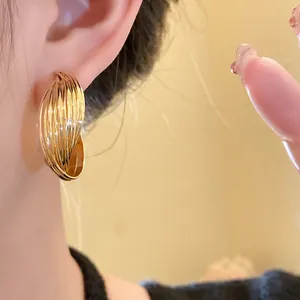 Detailed macro view of elegant gold multi-layer twisted hoop earrings worn on ear