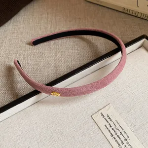 Detailed view of a pink flocked fabric headband featuring a gold Love charm detail