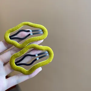 Close-up detail of moss green flocked irregular wavy BB hair clips held in human hand