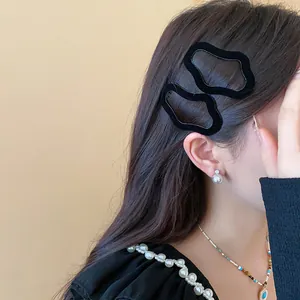 Detailed view of black flocked irregular geometric hair clips on a model's hair.