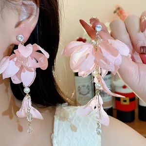 Primo piano di orecchini a fiore in tessuto rosa con perle e cristalli su modella