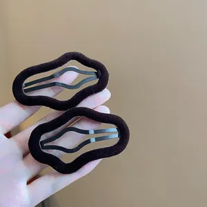 Close-up of black flocked irregular wavy hair clips showing soft texture and metal base.