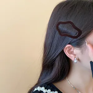 Close-up detail of dark brown flocked irregular geometric hair clip on model hair for winter