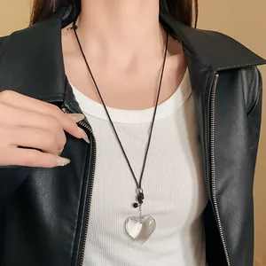 Close-up of a transparent heart-shaped pendant necklace on a black leather jacket