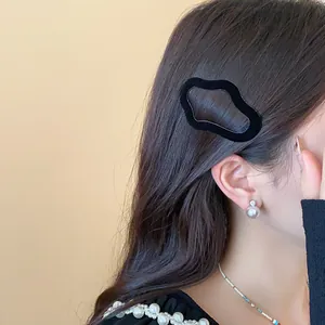 Close-up of a stylish black flocked irregular geometric hair clip worn by a model.