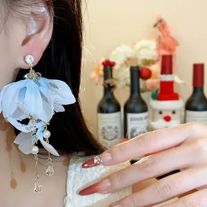 Eleganti orecchini a fiore in tessuto celeste con perle e cristalli mostrati su modella