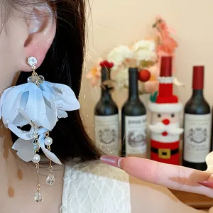 Primo piano di eleganti orecchini a fiore in tessuto azzurro con perle e cristalli.