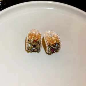Close-up of geometric arched earrings with gradient crystals and mini pearl border.