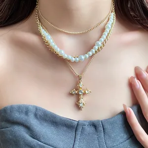 Close-up of vintage multi-layer pearl necklace with ornate rhinestone cross pendant and gold chain