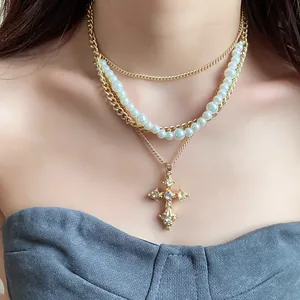 Detailed shot of layered gold necklace with pearls and ornate rhinestone cross pendant