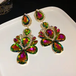 Detailed view of iridescent teardrop rhinestone dangle earrings on a white plate