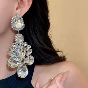 Detailed view of sparkling oversized water drop rhinestone earrings on model