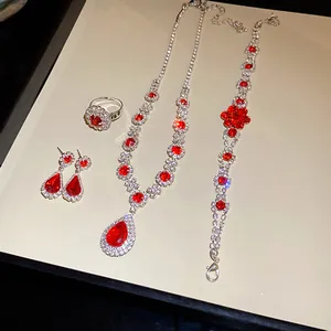 Luxury jewelry set with red teardrop pendant necklace, bracelet, earrings, and a ring.