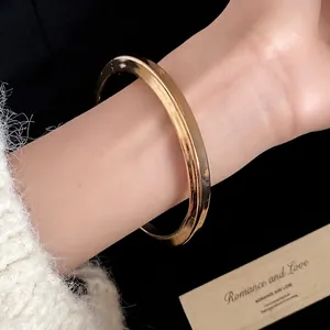Bracciale rigido minimalista in resina dorata con finitura lucida e liscia indossato al polso