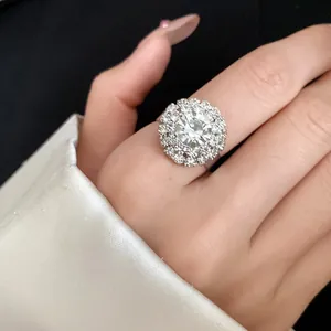Close-up of vintage palace style silver ring with round floral diamond setting on finger.