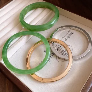 Dettaglio ravvicinato di quattro bracciali rigidi minimalisti in resina e metallo.